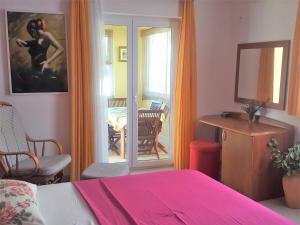 a bedroom with a pink bed and a table and chairs at Apartments Villa Novak in Slano