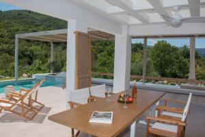 a patio with a table and chairs and a pool at Aristotelia Gi - Premium Luxury Villas with Private Pools in Olympiada