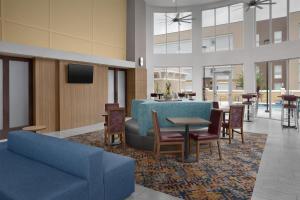 a lobby with a blue couch and tables and chairs at Hampton Inn & Suites Lake City in Lake City