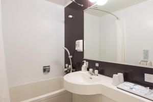 a white bathroom with a sink and a mirror at Comfort Hotel Naha Prefectural Office in Naha +40 photos