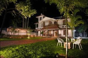 a house with two chairs in the yard at night at Casa de Victoria in Alleppey