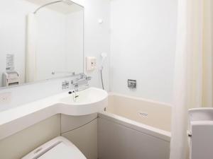 a bathroom with a sink and a toilet and a mirror at Comfort Hotel Hachinohe in Hachinohe +26 photos