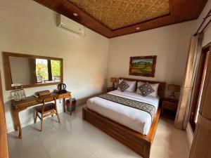 a bedroom with a bed and a desk and a window at Raka Rai House in Ubud