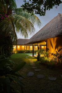 a building with a thatched roof and a yard at Akilea Villas Bali in Uluwatu