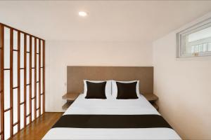 a bedroom with a bed with black and white pillows at Townhouse Oak The Vinhill Studio in Bangli +37 photos