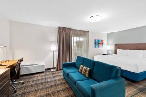a hotel room with a bed and a blue couch at MainStay Suites El Centro I-8 in El Centro +24 photos