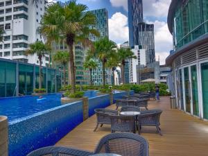 a pool on the roof of a building with tables and chairs at VORTEX Suites KLCC Premium BY RRP in Kuala Lumpur