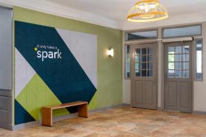 a lobby with a bench and a wall with a spark sign at Spark by Hilton Watertown, NY in Watertown