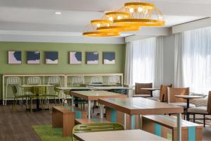 a dining room with tables and chairs and lights at Spark by Hilton Watertown, NY in Watertown
