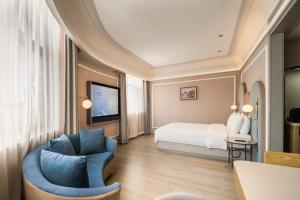 a hotel room with a bed and a chair at Mercure Qingdao Downtown in Qingdao