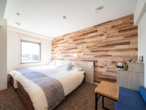 a bedroom with a large bed and a wooden wall at Super Hotel Premier Shimonoseki in Shimonoseki