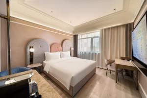 a hotel room with a bed and a flat screen tv at Mercure Qingdao Downtown in Qingdao +47 photos