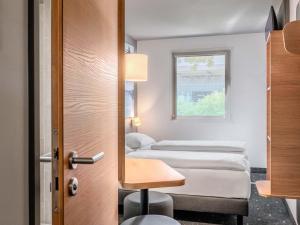 a row of beds in a room with a window at B&B HOTEL Regensburg-Ost in Regensburg