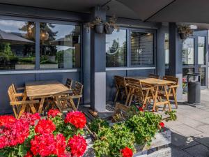 two tables and chairs on a patio with red flowers at B&B HOTEL Regensburg-Ost in Regensburg