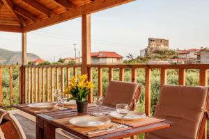 a wooden table with glasses and flowers on a deck at Selinitsa Stone Studio - Mani Seaview Retreat in Agios Nikolaos