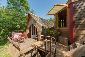 a cabin with a deck with a table and a chair at Les roulottes de Rita "Le poulailler" in Verfeil-sur-Seye