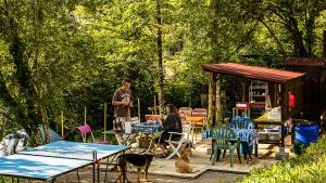 a man and a woman in a yard with tables and chairs at Les roulottes de Rita "Le poulailler" in Verfeil-sur-Seye