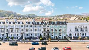 a large white building with cars parked in a parking lot at Sea View, East Parade in Llandudno