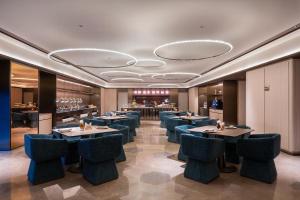 a restaurant with blue chairs and a bar at Orange Crystal Hotel Kunming Haile World in Kunming