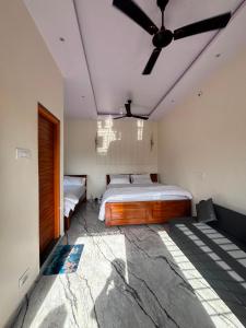 a bedroom with two beds and a ceiling fan at Hampi Tribes Homestay in Hampi
