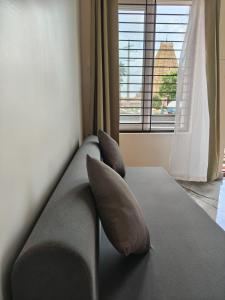 a couch with two pillows in a room with a window at Hampi Tribes Homestay in Hampi +3 photos