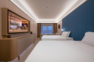 a hotel room with two beds and a flat screen tv at Orange Crystal Hotel Kunming Haile World in Kunming