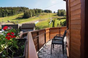a balcony with two chairs and a view of a field at Penzion Praděd in Malá Morávka