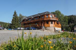 a large wooden house in the middle of a parking lot at Penzion Praděd in Malá Morávka