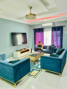 a living room with blue couches and a tv at Yoyo Kunda in Banjul