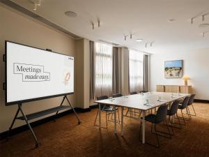 a meeting room with a white screen and a table and chairs at Adina Sydney Darling Harbour in Sydney