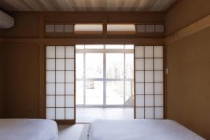 two beds in a room with a large window at rinne 那須 Garden 3 in Nasu