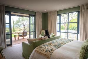 a woman sitting on a bed in a room with windows at Brookdale Estate - Manor House in Paarl +71 photos