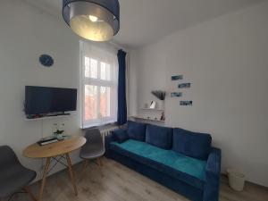 a living room with a blue couch and a table at Magnolia Home Rooms in Toruń