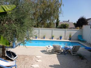 a swimming pool with two chairs and a table next to it at Chambre bleue avec accès plage in Bourges