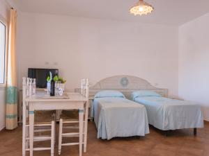 a room with two beds and a table and a tv at Le Residence del Golfo Orosei in Orosei