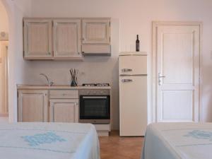 a kitchen with white cabinets and a white refrigerator at Le Residence del Golfo Orosei in Orosei