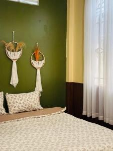 a bedroom with a bed and two plants on a green wall at Phòng Mơ - Nhà Mơ Homestay Bến Tre in Ben Tre