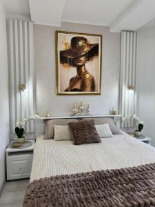 a bedroom with a large bed with a painting on the wall at Angel Luxury Apartment in Kikinda
