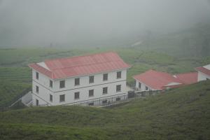 a white building with a red roof on a hill at Kanyam Brichyalaya in Suryodaya