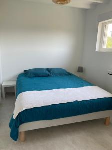 a bed with blue and white sheets and a window at Préchacq-les-Bains in Préchacq