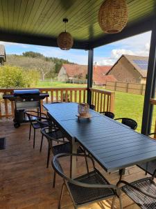 a blue table and chairs on a deck with a grill at Chalet familial avec piscine chauffée, jeux et brasero- Morvan in Voudenay-lʼEglise