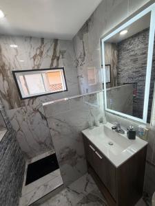 a marble bathroom with a sink and a mirror at Alvin Relax in El Cajon