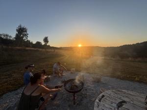 a group of people sitting around a grill at sunset at Luxury Glamping - Heydaze in Lostwithiel