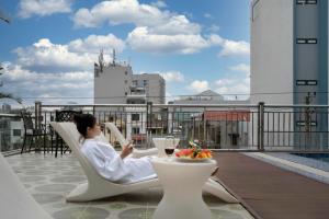 a woman sitting in a chair on a balcony with a glass of wine at Hùng Vương Hotel - Stay 24h in Móng Cái