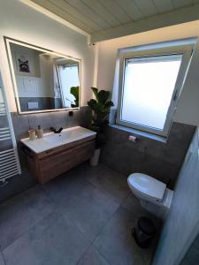 a bathroom with a sink and a toilet and a window at Ferienwohnung Burgjuwel Burghausen nahe weltlängster Burg zentral 24h Check in in Burghausen