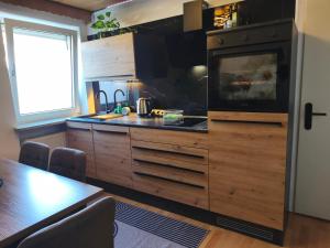 a kitchen with wooden cabinets and a stove top oven at Ferienwohnung Burgjuwel Burghausen nahe weltlängster Burg zentral 24h Check in in Burghausen +8 photos