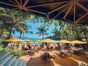 a beach with chairs and umbrellas and palm trees at 1404, Building 1, Ocean Sky Forest - Flamingo Cat Ba in Cat Ba