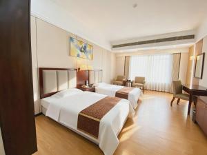 a hotel room with two beds and a desk at Yinfeng Hotel Guangzhou North Station Branch, Huacheng Road Subway Station Branch in Huadu