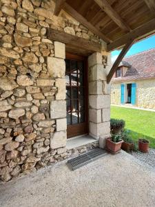 a stone house with a wooden door and a stone wall at Chez Fayolle in Montagnac-la-Crempse