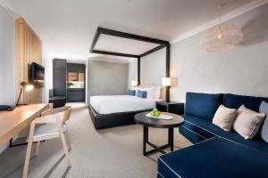 弗里曼特Tradewinds Hotel and Suites Fremantle的一间带床和蓝色沙发的酒店房间